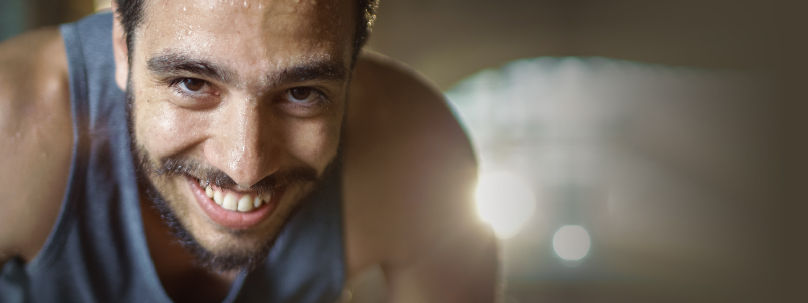 Sportieve man met een baard ziet er glimlachend uit en zwet de kijker