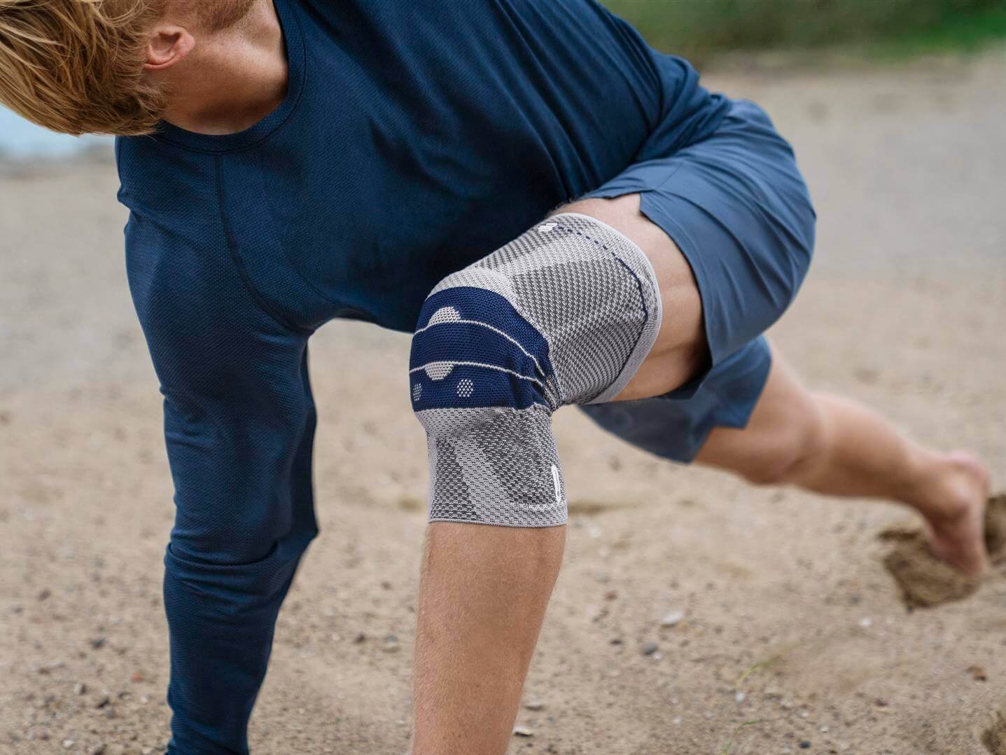 Uitsnede van een man met een GenuTrain bandage om zijn knie. Die biedt ontlasting en stabiliseert de knie om pijn te verlichten.