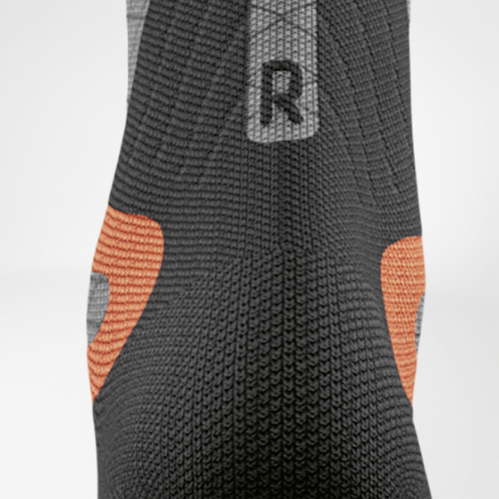 Detailweergave van de rechter ski-compressiekous voor dames van Bauerfeind. Zichtbaar zijn de oranje hielpads en het zwarte breisel voor gerichte ondersteuning in de schoen.