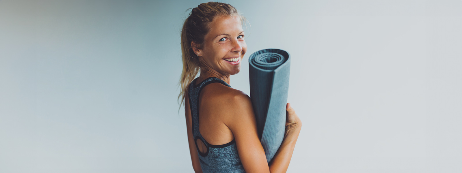 Glimlachende vrouw met een yogamat