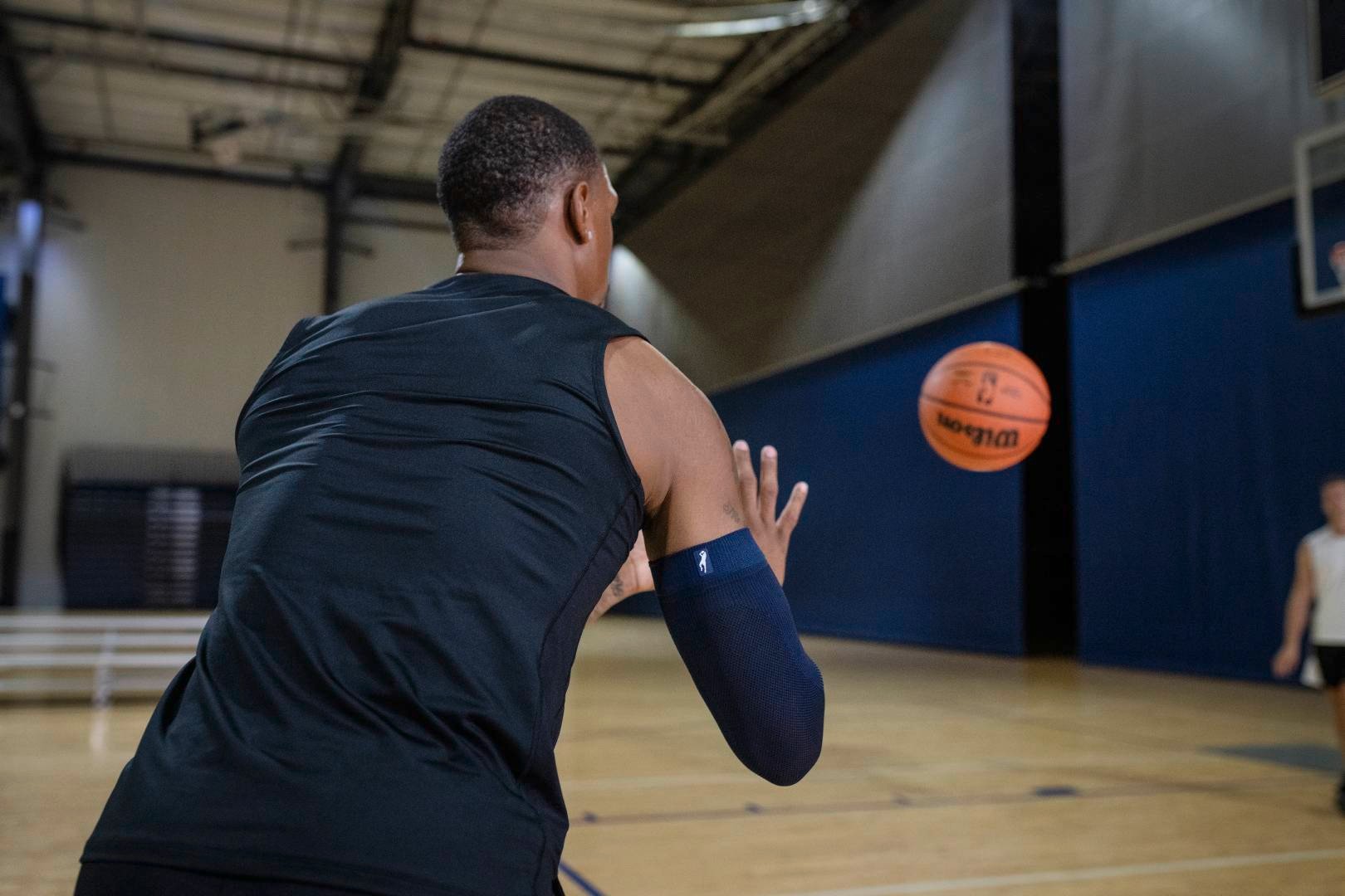 Basketbalspelers met een Blue Armsleeve in Sports Hall wacht op een bal die door een andere speler naar hem wordt gegooid