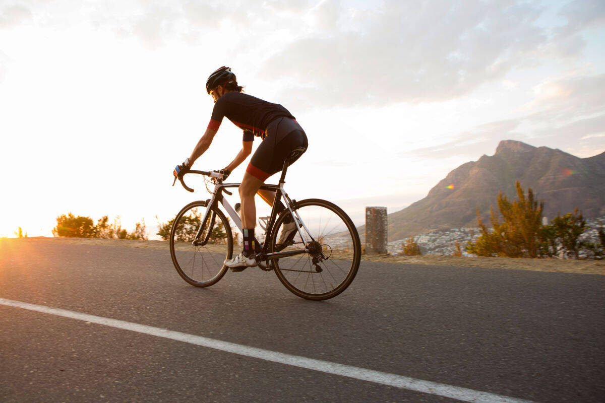 Vrouw rent op een racefiets op een straat richting zonsondergang