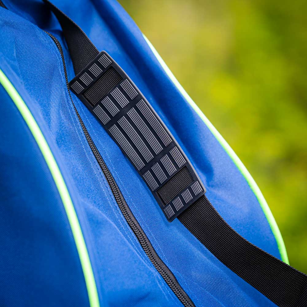 Close-up van een gevoerde zwarte schouderriem op een blauwe tas met groene accenten. De riem heeft een gestructureerd oppervlak voor extra grip.