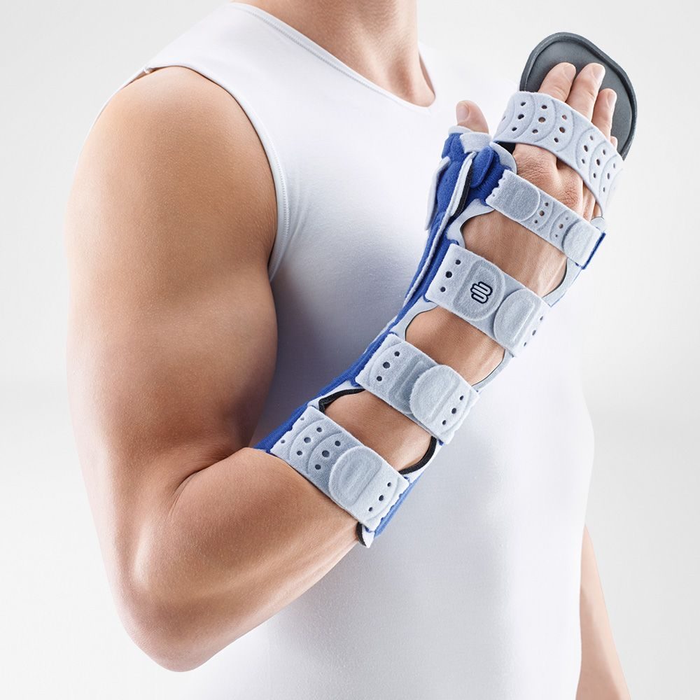 Persoon met gebogen arm draagt een verstelbare pols- en handspalk met grijze banden en blauwe steun.