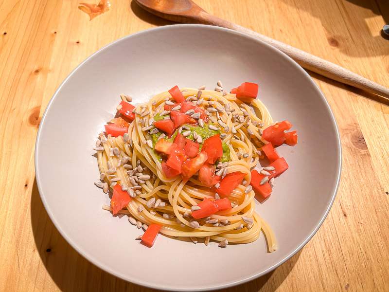Een bord spaghetti met verse tomaten en zonnebloempitten, ideaal voor een koolhydraatrijke maaltijd voor een halve marathon.