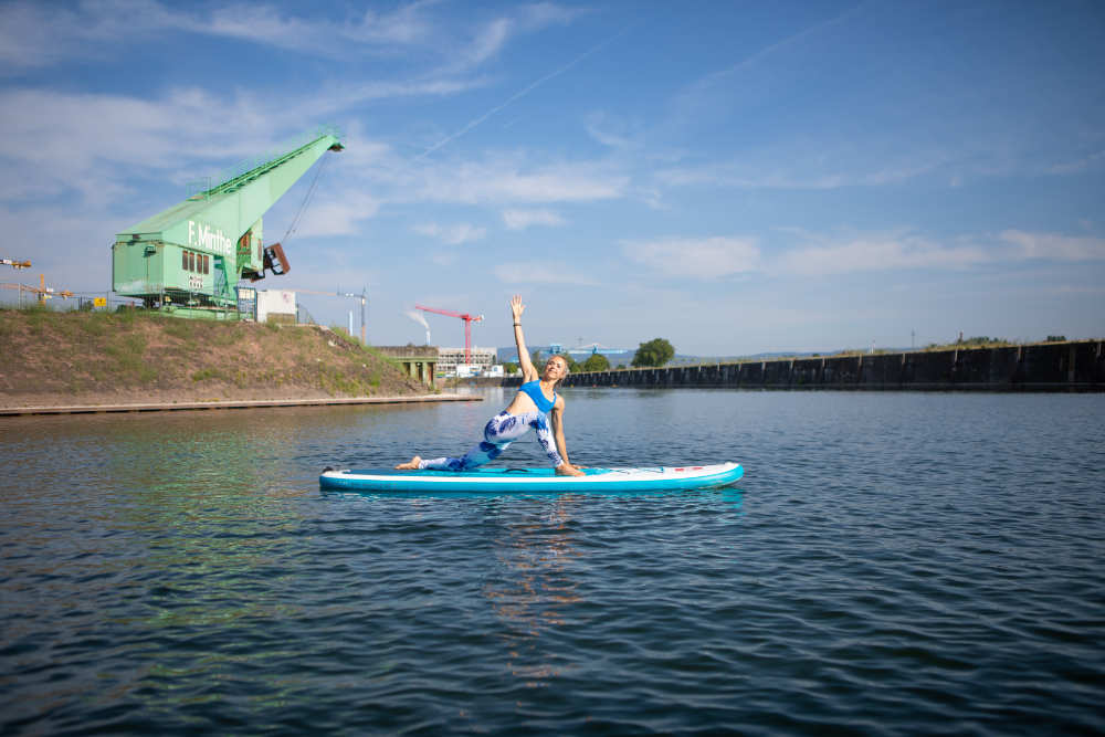 Vrouw maakt yoga -oefening op het bord met kranen op de achtergrond