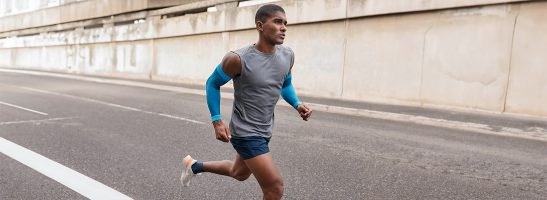 Runner met blauwe arm mouwen loopt door de stad op een straat