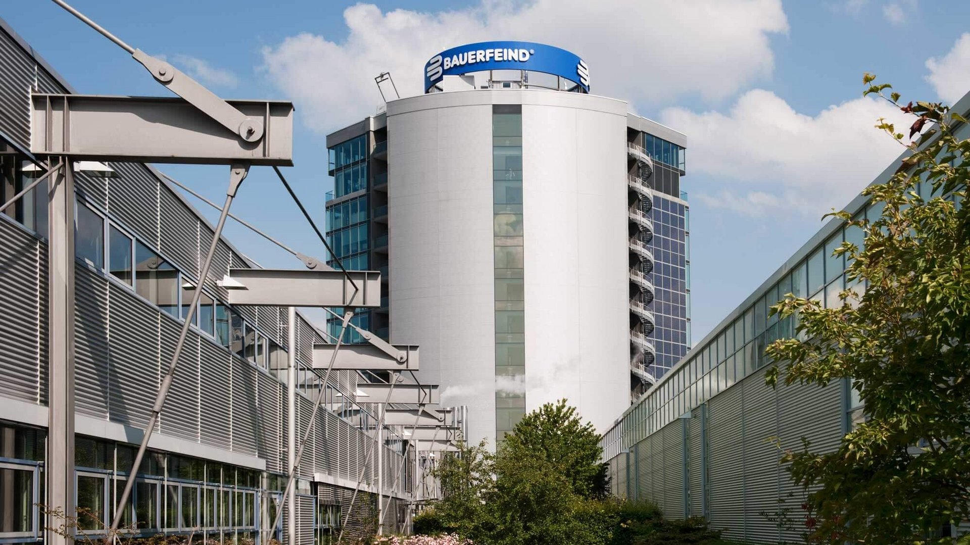 Zijaanzicht van de moderne Bauerfeind-toren in Zeulenroda: een gebouw met meerdere verdiepingen, een strakke architectuur van glas en staal, omgeven door groen aangelegde buitenruimtes.