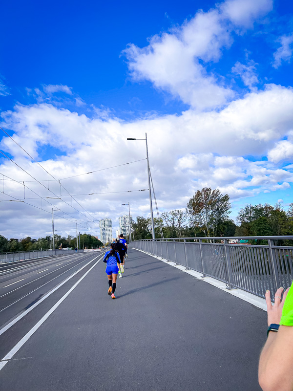 Hardlopers op een brug vechten tegen een sterke tegenwind zonder de hulp van een beschermende groep tijdens de halve marathon.
