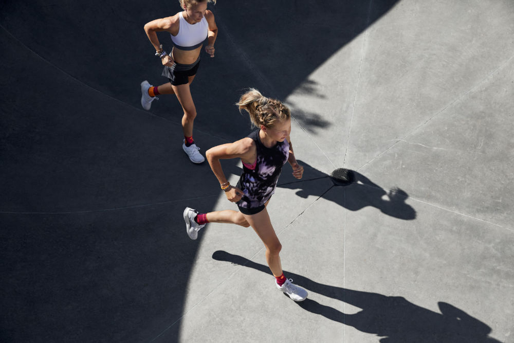 Lopers met enkelbandages lopen in een zomeroutfit over een betonnen oppervlakperspectief van rare top