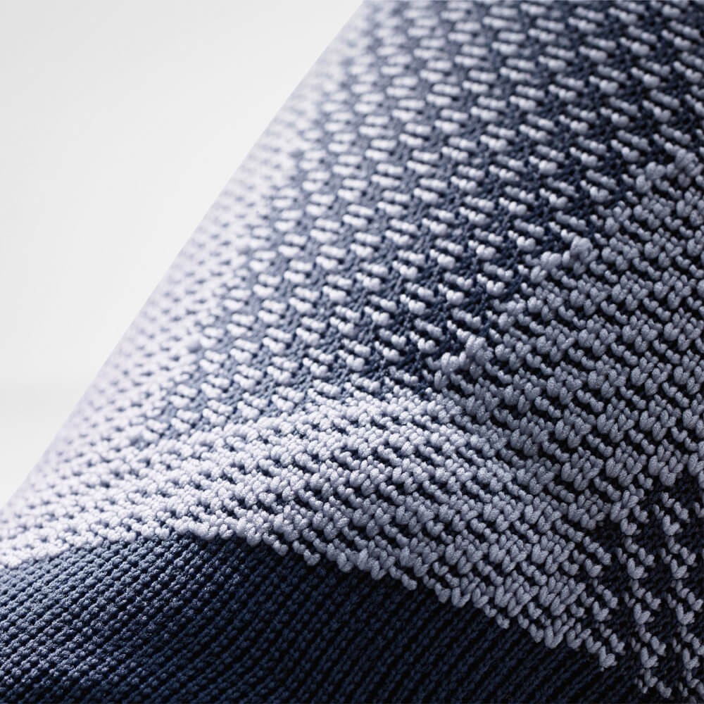 Close-up van zijstabilisator van kniebrace met blauwe steunband en compressiebreisel.