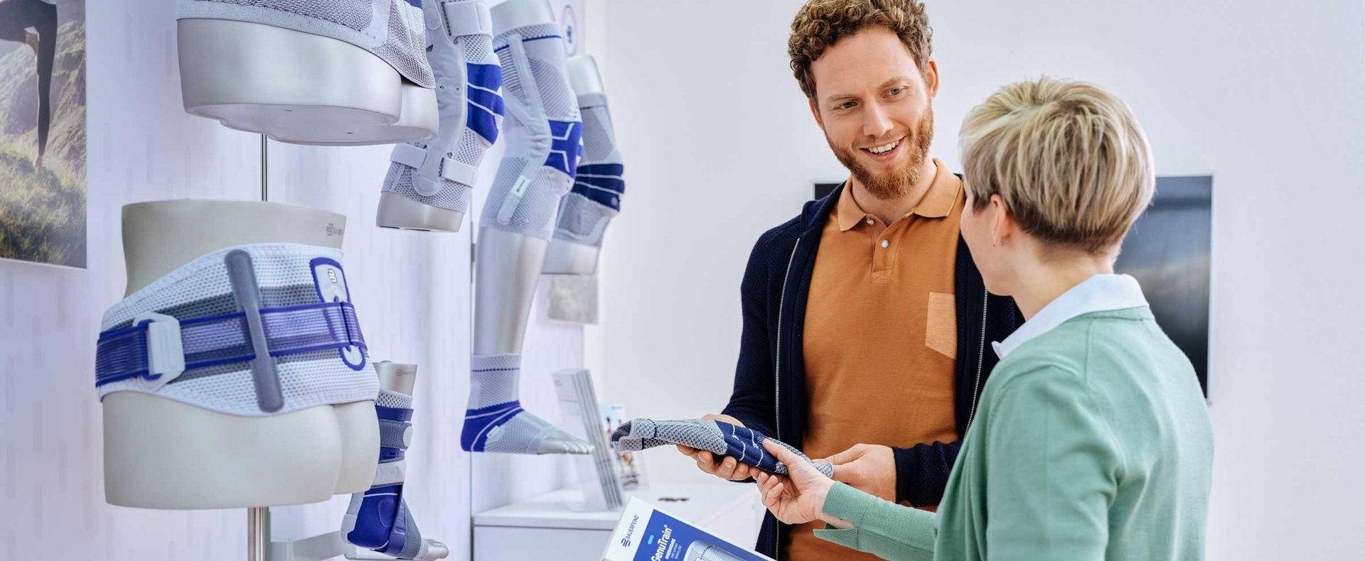 Adviesgesprek over bandages: een persoon laat iemand die hulp zoekt een bandage zien en legt het gebruik ervan uit. Op de achtergrond zie je advieselementen zoals informatiemateriaal of displays.