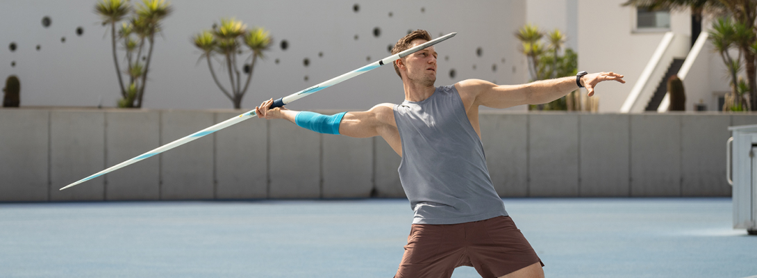 Man traint de speerworp en draagt ​​een sportleeve voor de elleboog
