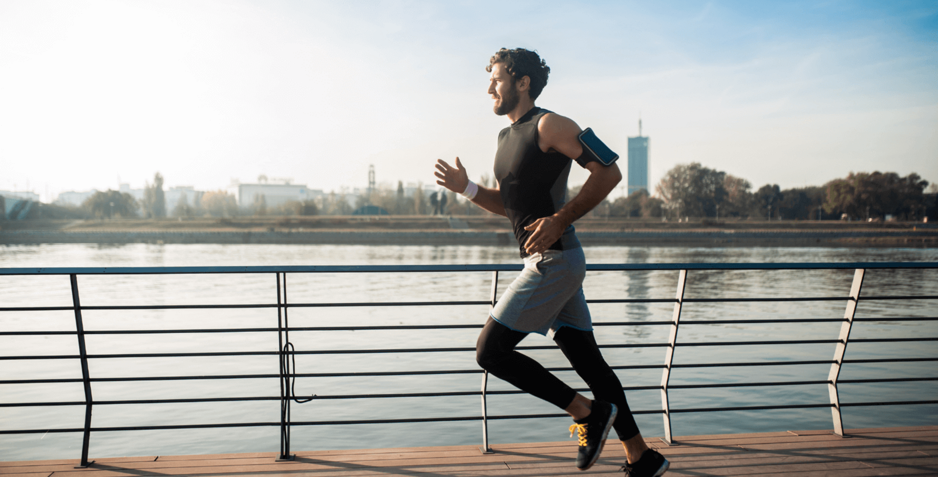 Op het beeld zie je een man die langs een rivier joggt.