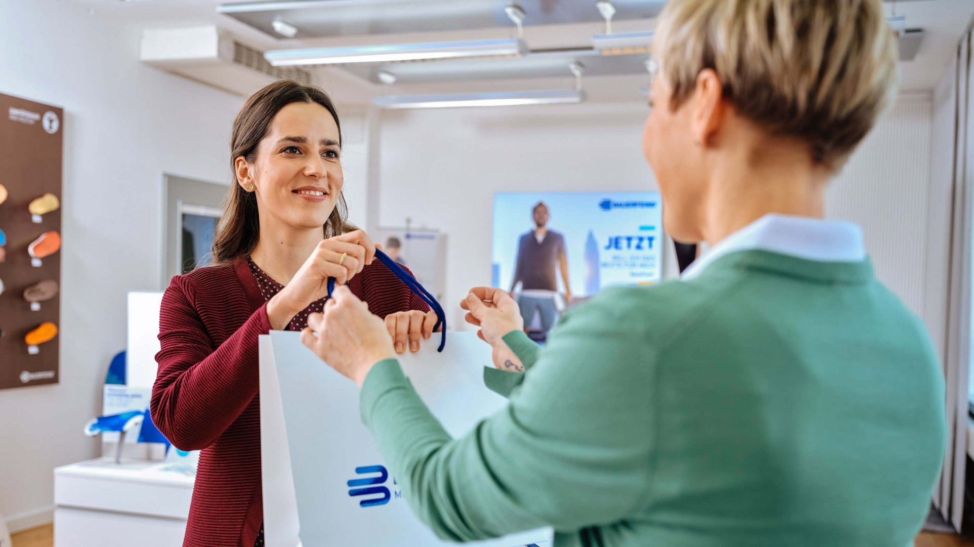 Te zien zijn twee vrouwen in een adviesgesprek in de medische speciaalzaak over de hulpmiddelen van Bauerfeind.