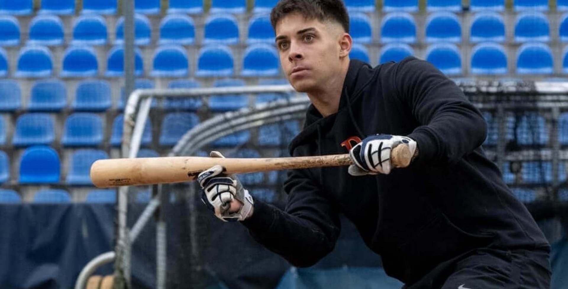 Honkballer Simon Liedtke zit gehurkt bij de home plate en focust zich op de bal die op hem afkomt. Hij draagt de SecuTec Genu Flex knieorthese om zijn achterste kruisband te stabiliseren.