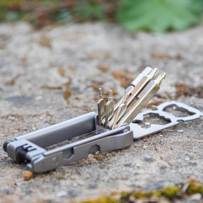 Uitgeklapte Bauerfeind Sports multitool met meerdere bits en gereedschapsfuncties op een stenen ondergrond buiten – perfect om onderweg flexibel te blijven en je fiets altijd rijklaar te houden.