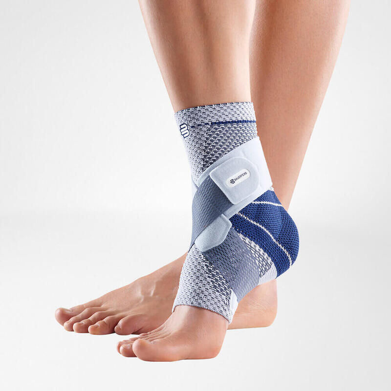 Vrouw in blauwe sportkleding stretcht aan zee met enkelbrace voor fitness en herstel.