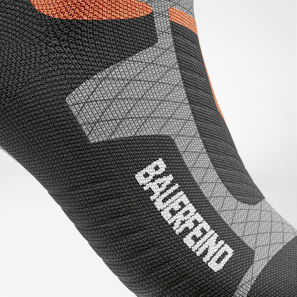 Detail van de zijkant van de voet van de ski-compressiekous voor dames met duidelijk zichtbaar BAUERFEIND-logo en ergonomische structuur.