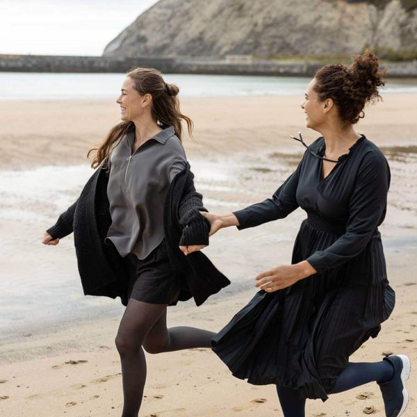Twee vrouwen lopen op het strand. Beiden dragen VenoTrain micro compressiekousen van Bauerfeind.
