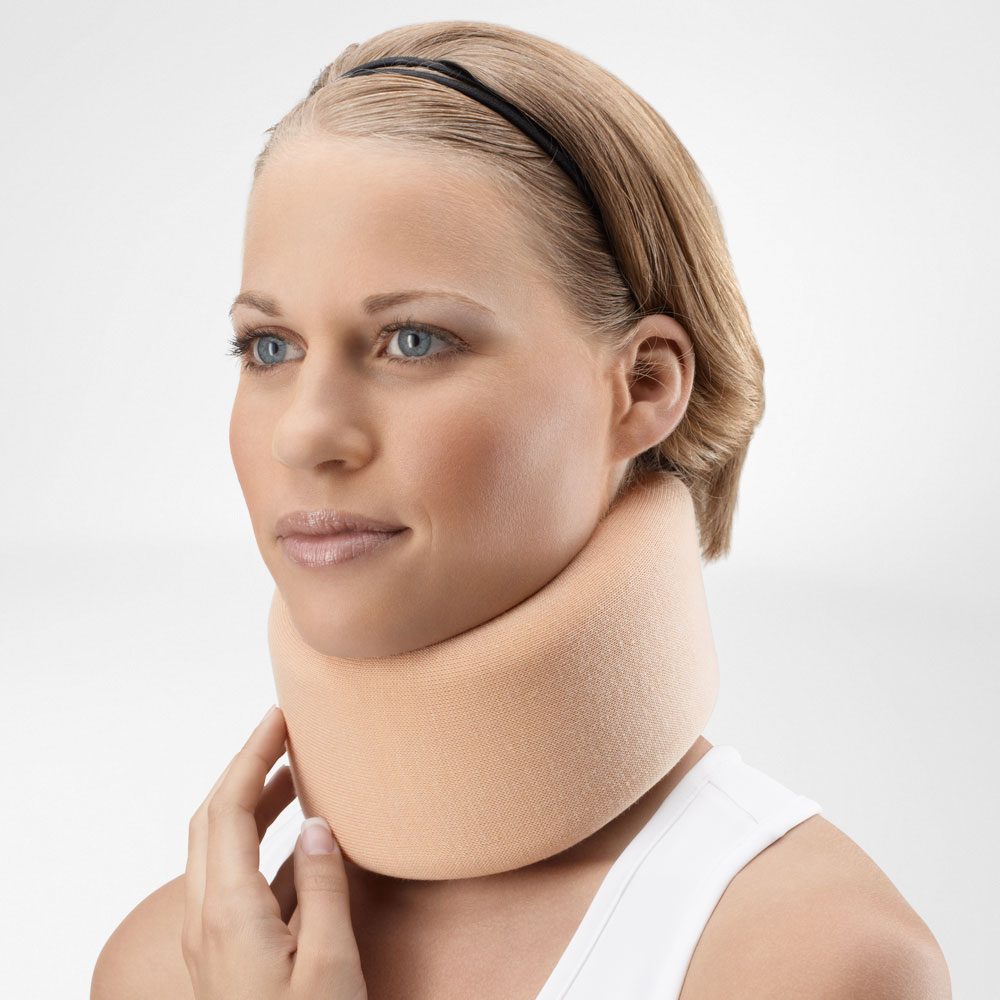 Vrouw met een beige nekbrace rond haar hals tegen een lichte achtergrond.