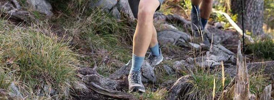 Zwante vrouw op een steenachtig oppervlak draagt ​​middellange wandelsokken